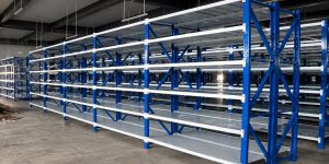 Rayonnage mi-lourd à tablettes, montants bleus et lisses blanches, installé en entrepôt